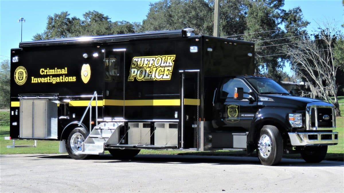 A large black Suffolk Police Criminal Investigations truck, equipped with Homeland Security features, is parked outdoors on a paved surface with trees in the background.