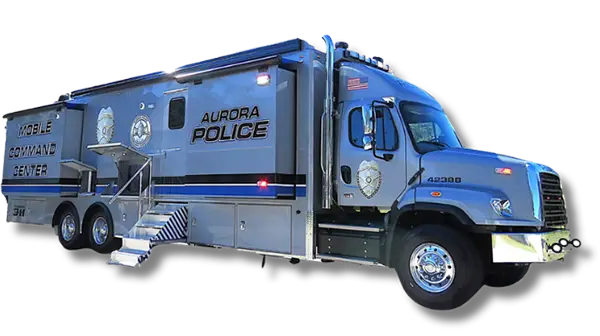A large silver Aurora Police Mobile Command vehicle is parked, featuring multiple wheels, steps leading to an entrance, official police logos, and the words “Mobile Command Center” and “Aurora Police” on the side.