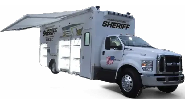A large white Hillsborough County SWAT support vehicle features an extended awning, multiple storage compartments, and an American flag decal on the door.