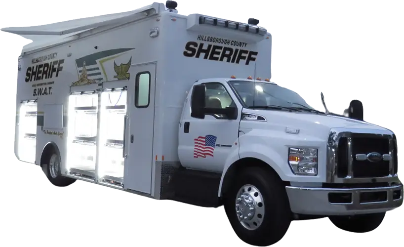 A large white Hillsborough County SWAT Support Vehicle with multiple compartments open on the side, emergency lights on top, and an American flag decal on the door.