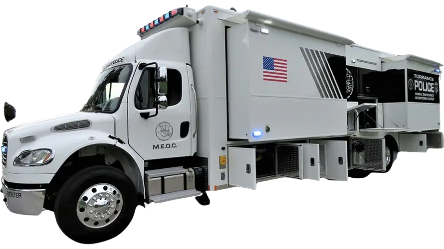 A large white Mobile Emergency Operations Center truck with police markings, an American flag decal, external storage compartments, and emergency lights on the roof.