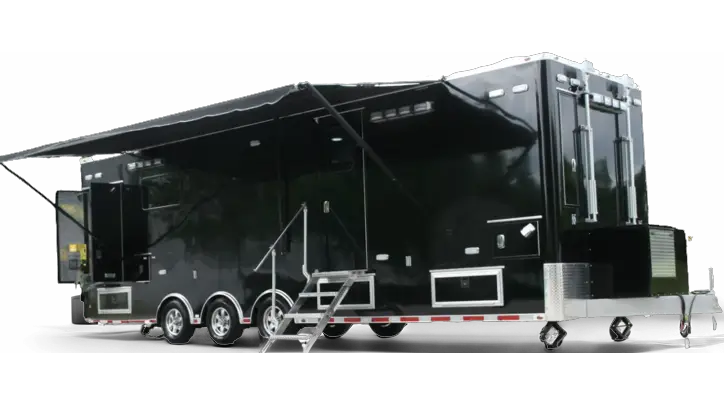 A large, black Rehab Unit Trailer with three axles, multiple windows, an extended awning, external storage compartments, and a set of metal stairs leading to a side door—ideal for Brentwood Legion or Volunteer Ambulance support.