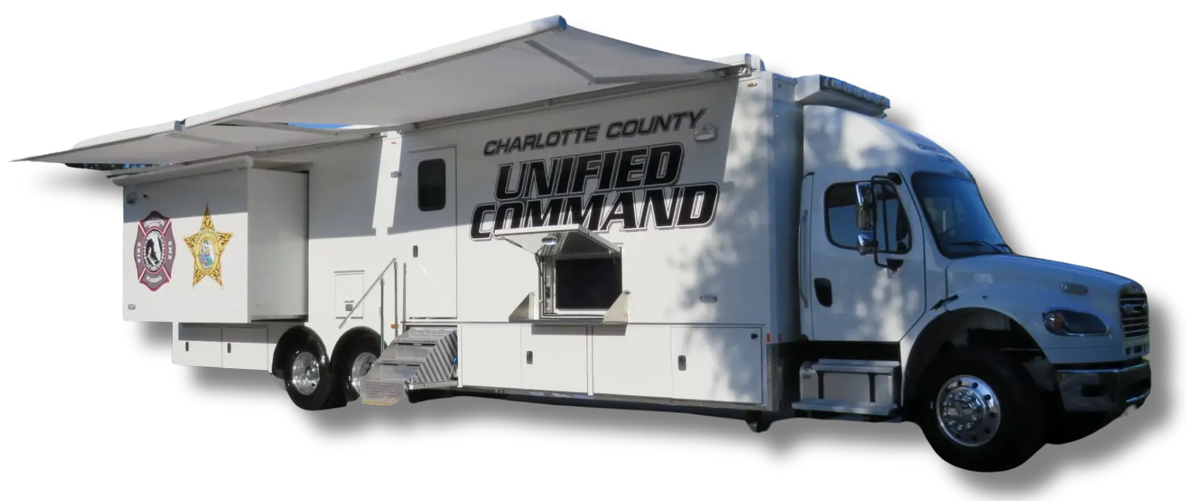 A large white mobile command vehicle labeled Charlotte County Unified Command with emergency service logos, extended awnings, and side compartments open, similar in function to a Volusia County Sheriffs Office Public Safety Vehicle, parked on a white background.