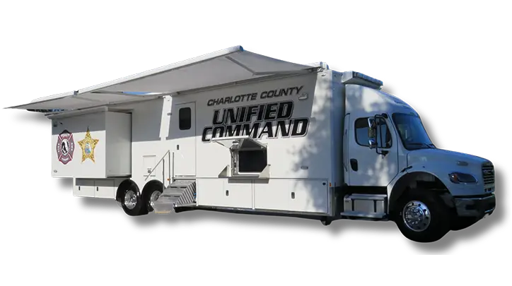 A large white command vehicle labeled Charlotte County Unified Command with emergency service logos, steps leading to a side door, and an extended canopy—similar in purpose to a Volusia County Sheriffs Office Public Safety Vehicle.